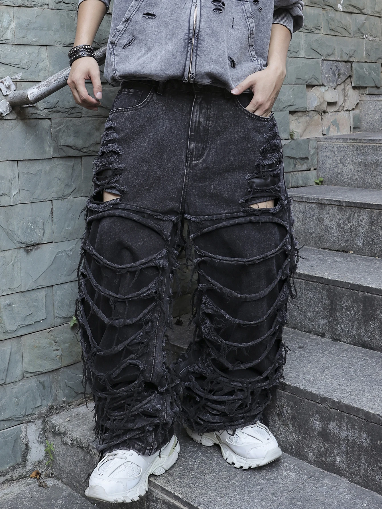 Men's black jeans. With a design of (ripped holes) and tassels. In a street trend style.